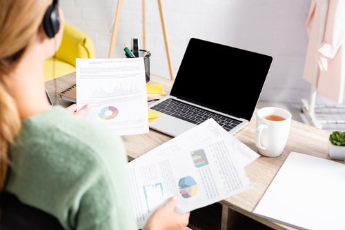 This image shows a woman working on a computer and looking at graphs. Analyzing your financial situation is an important aspect of your dance studio business plan.